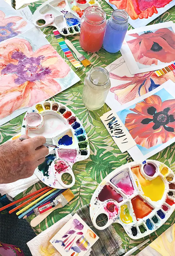 Expressive botanical watercolours in progress, with palettes and brushes