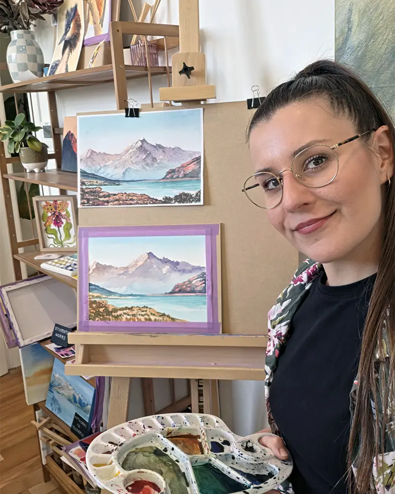Kasia Hebda at the easel with two Aoraki / Mt Cook watercolours after a landscape workshop in her Queenstown studio