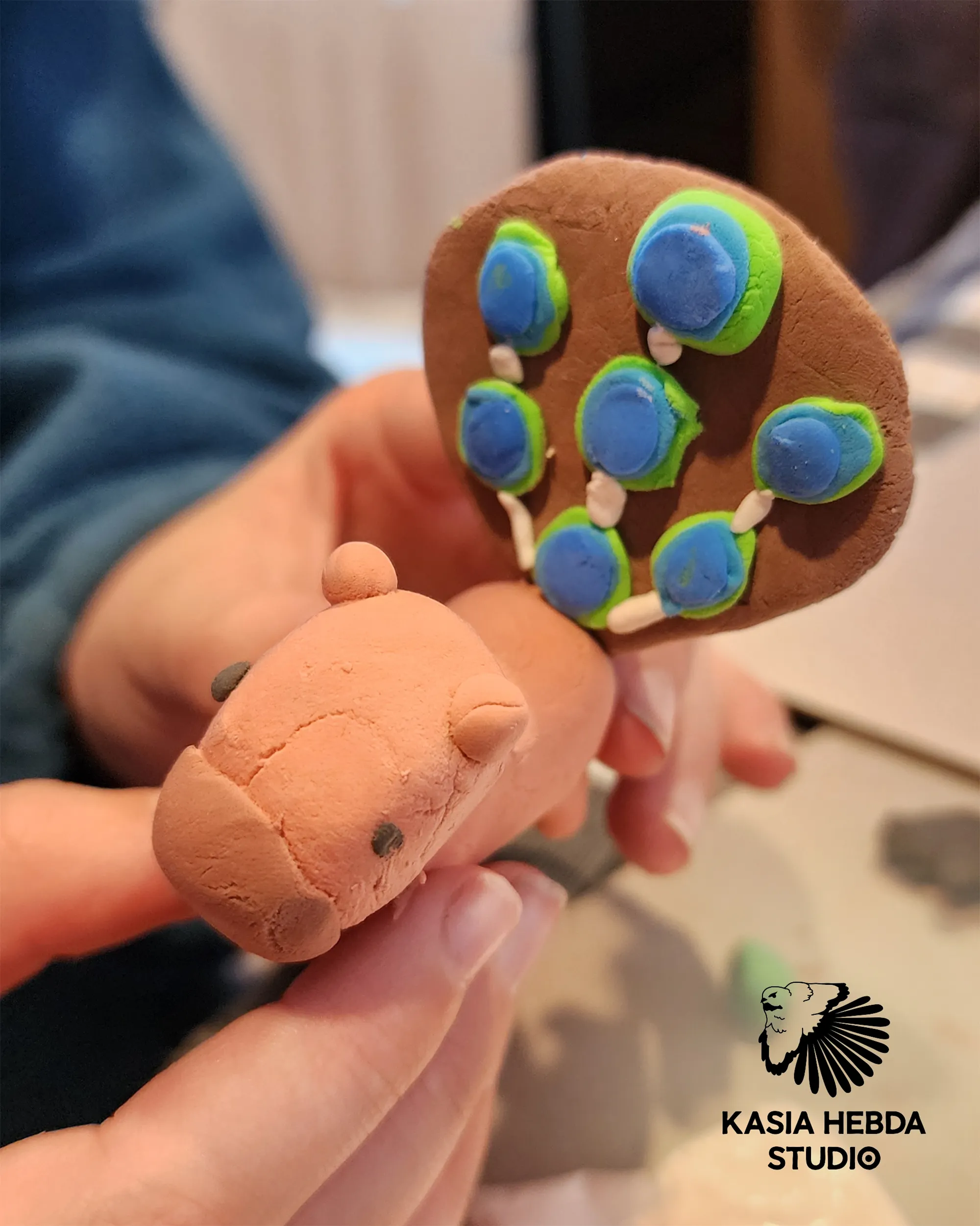 A student holding a small painted clay animal they made