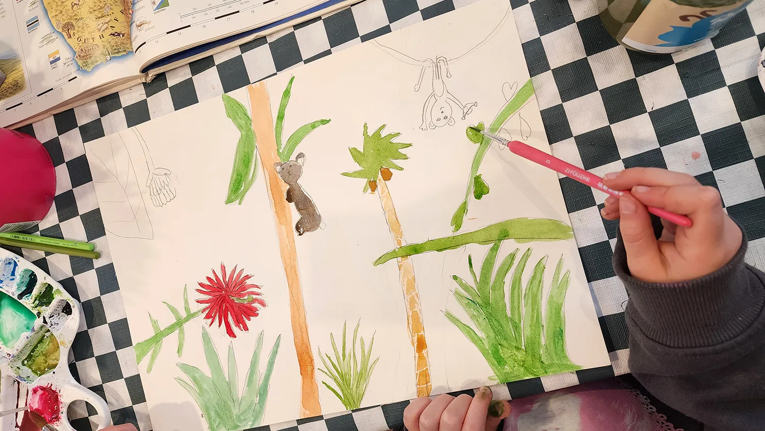 A student painting a jungle scene of palms and ferns in watercolour