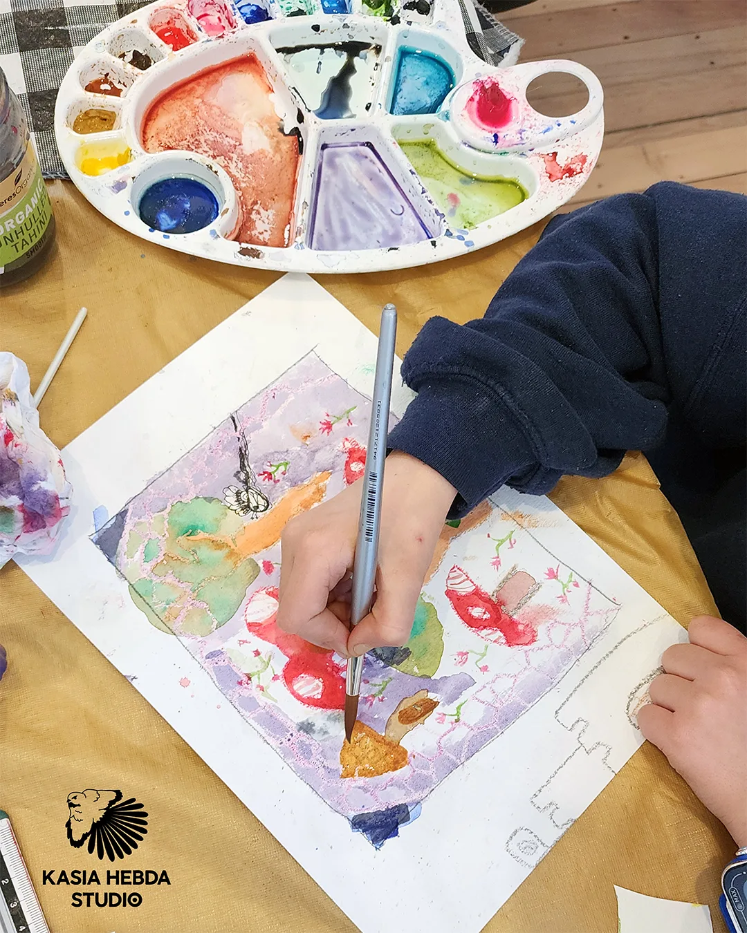 Overhead view of a student mixing watercolours beside their painting