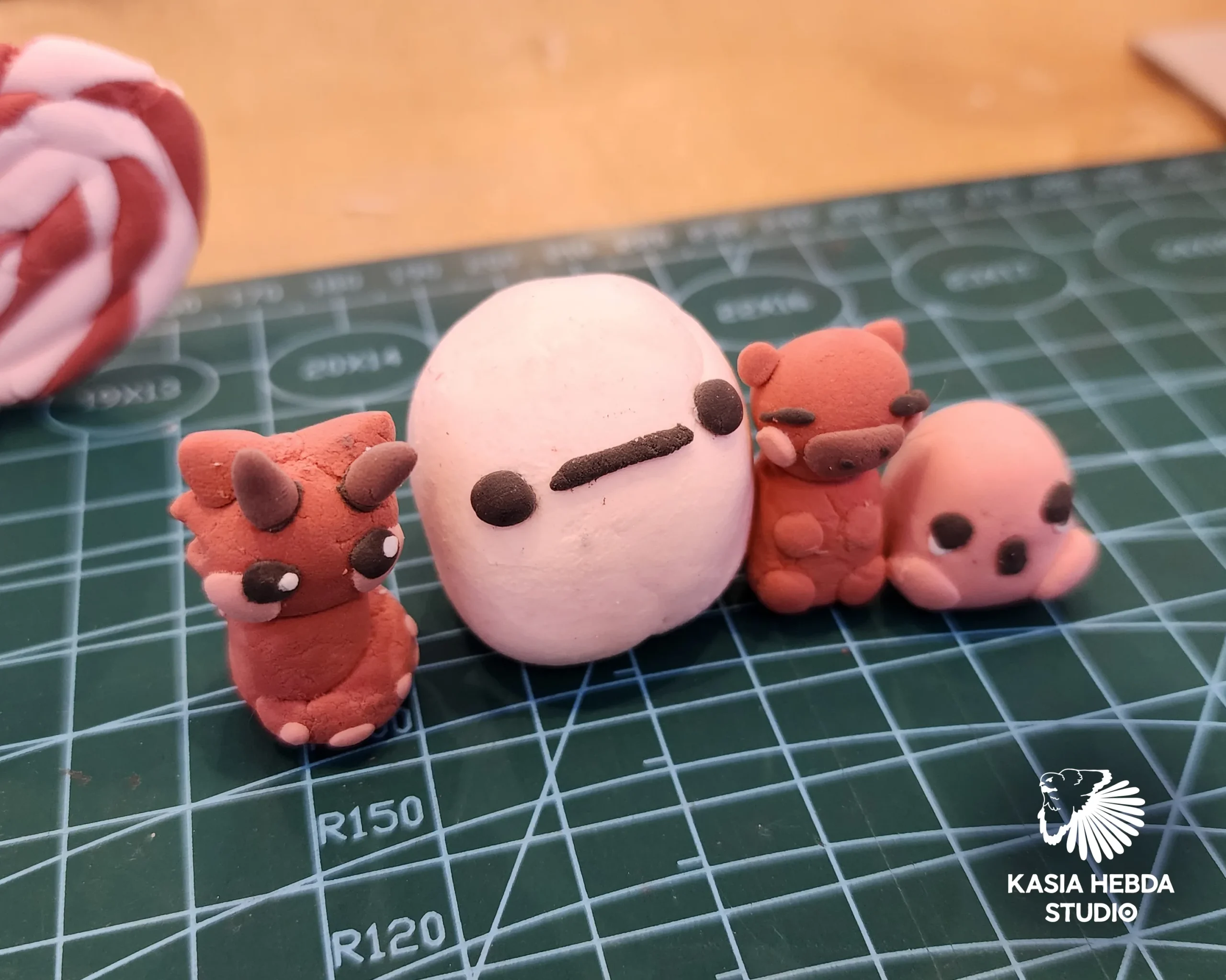Small air-dry clay characters made by students, lined up on a cutting mat